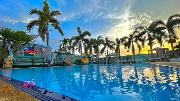 A swimming pool with palm trees and a sunset in the background. - Villa Na Wande Sattahip (Sattahip)