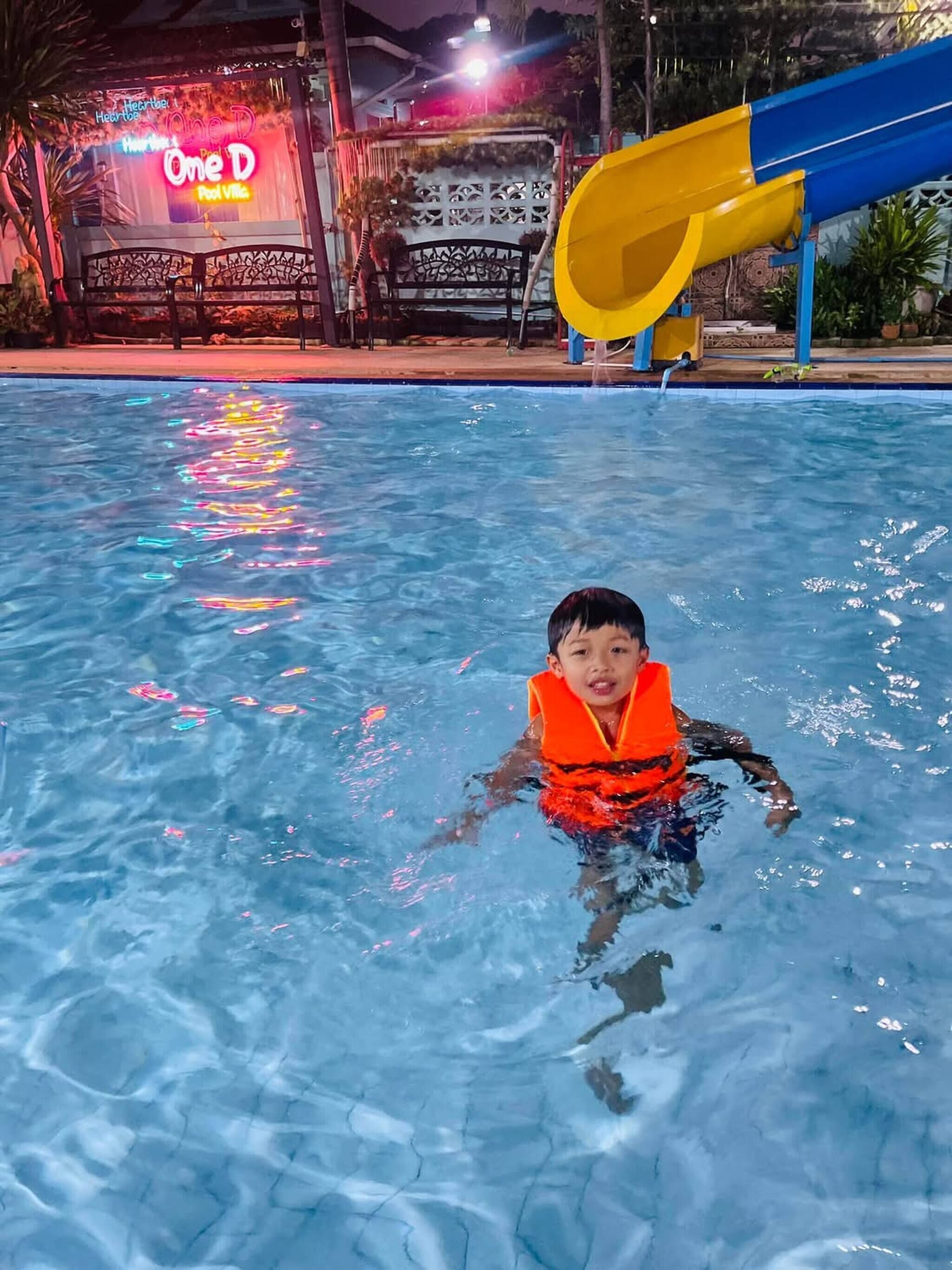 A child in a pool wearing a life jacket.