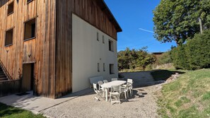 Um edifício com fachada de madeira e um pátio de cascalho com mesa e cadeiras.