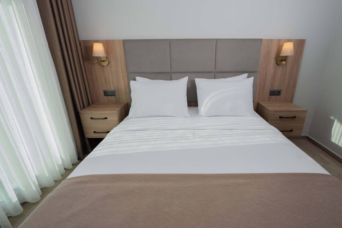 A hotel room with a large bed, two bedside tables, and a headboard.