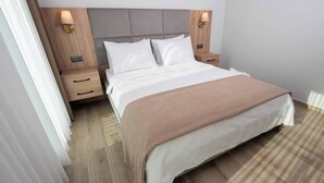 A neatly made bed with a headboard, two bedside tables with lamps, and a wooden floor. - Altındere Vadi Hotel (Akyazi)