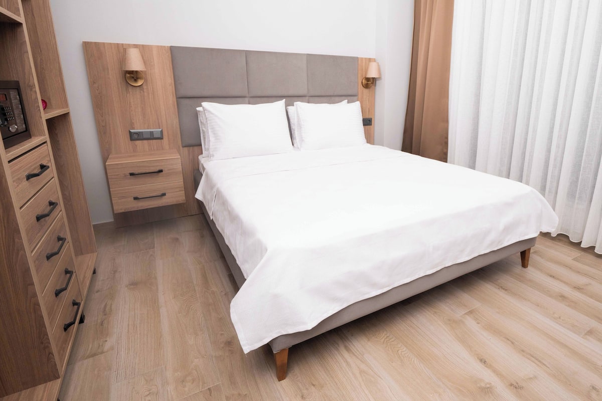 A neatly arranged hotel room with a bed, bedside tables, a wardrobe, and a lamp.