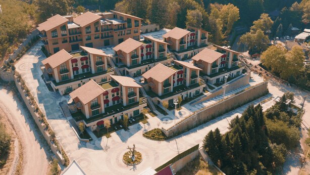 Un moderno complejo hotelero con varias edificaciones, zonas de estar al aire libre y un patio central.