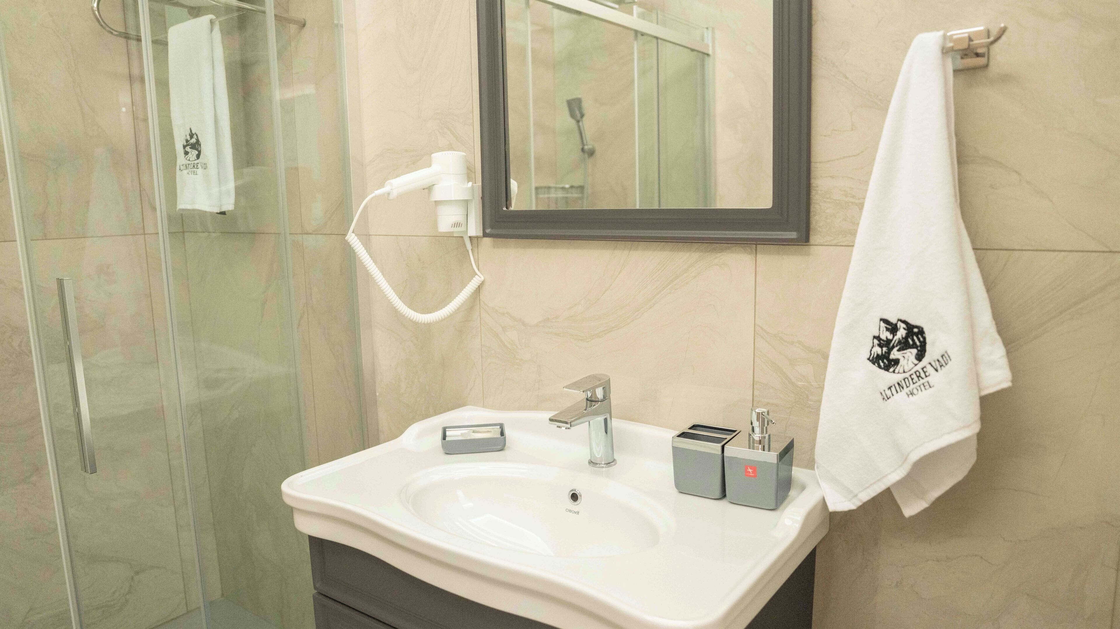 A bathroom with a white sink, a mirror, and a towel hanging on the wall.