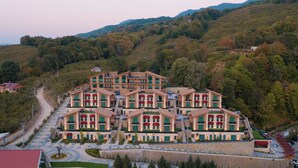 A multi-story hotel with a central courtyard, surrounded by lush greenery and hills. - Altındere Vadi Hotel (Akyazi)