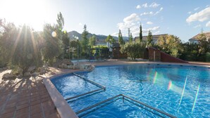 A swimming pool with a clear sky, trees, and buildings in the background. - Family-friendly Stay With Pool Access (Pozo Alcon)
