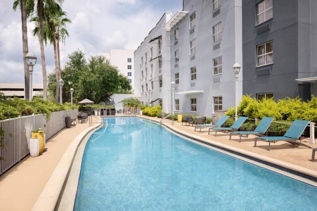 A swimming pool with lounge chairs and a building with multiple windows.