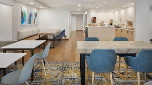 A modern dining area with a long table, blue chairs, and a patterned rug. - Fully Equipped Kitchen in Modern Suite with Airport Shuttle and Swimming Pool (Tampa)