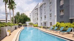 A swimming pool with lounge chairs and a building with multiple windows. - Fully Equipped Kitchen in Modern Suite with Airport Shuttle and Swimming Pool (Tampa)