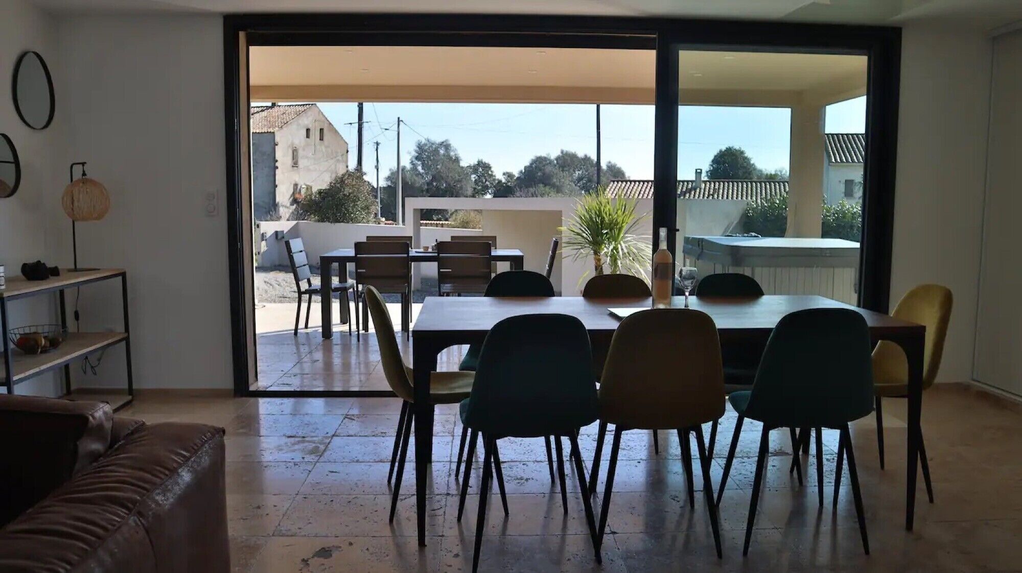 Een eetgedeelte met een tafel en stoelen, een bank en een schuifdeur naar een terras.