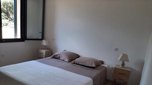 A bedroom with a bed, two bedside tables, and a window.