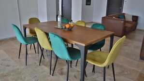 A dining area with a wooden table, six chairs, and a fruit bowl.