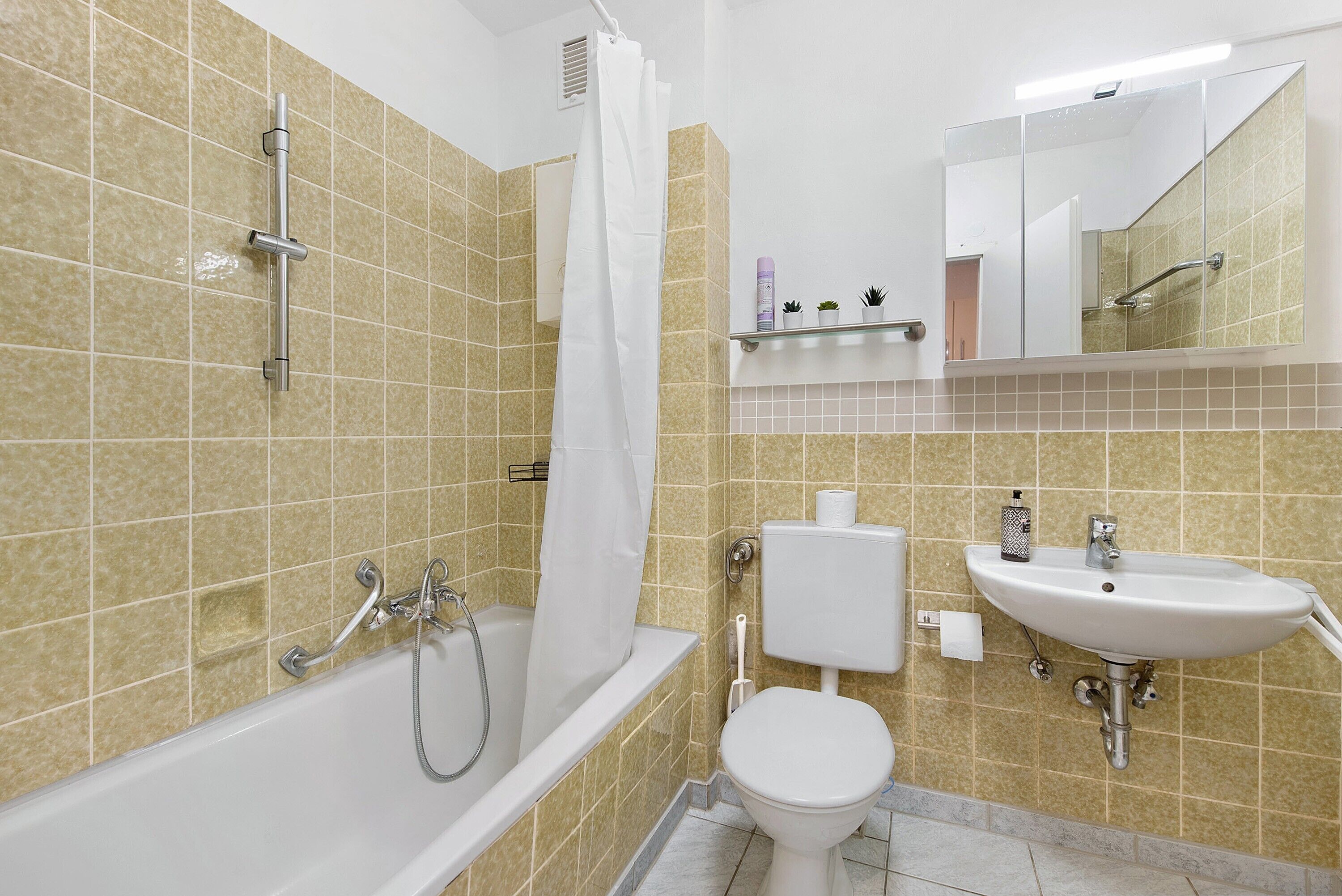 Une salle de bain avec une baignoire, des toilettes, un lavabo et un miroir.