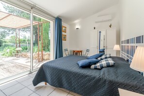 A bedroom with a bed, a window, a door, and a small table. - Gîte 'Romarin' with Mountain View, Wi-Fi and Air Conditioning (Entrechaux)