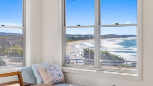A room with large windows overlooking a beach and ocean.