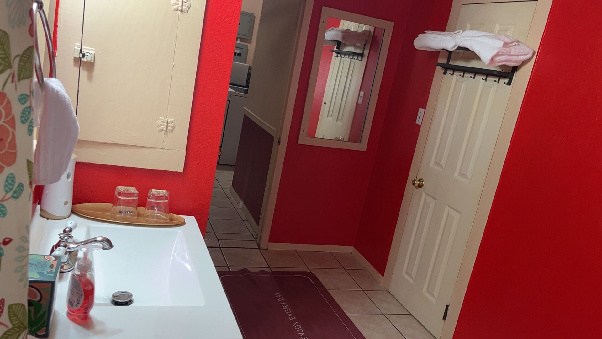 Une salle de bain avec un lavabo blanc, des murs rouges, un miroir et un porte-serviettes.