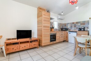 Ett modernt kök med TV, träskåp, mikrovågsugn och kaffebryggare.