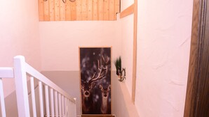 A staircase with a white railing, a wooden wall panel, a chandelier, and a deer painting. - Beim Patzelt - Holiday home Nesselwang | Königscard | Pets welcome (Nesselwang)