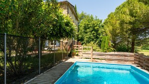 A swimming pool with a wooden deck, surrounded by trees and a fence. - Villa 'Le Mas' with Mountain View, Private Pool and Wi-Fi (Entrechaux)