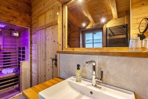L’intérieur d’une cabane en bois comprend une salle de bain équipée d’un lavabo, d’un miroir et d’une fenêtre.