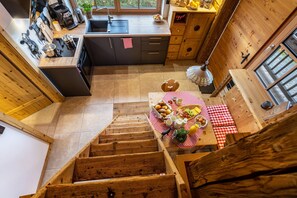 A wooden interior with a kitchen, dining area, and staircase.