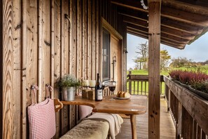 Une cabane en bois avec une table, un banc et une bouteille de vin, tous en bois.
