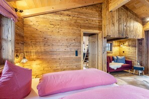 L'intérieur d'un chalet en bois, avec un lit, un canapé et une petite table.