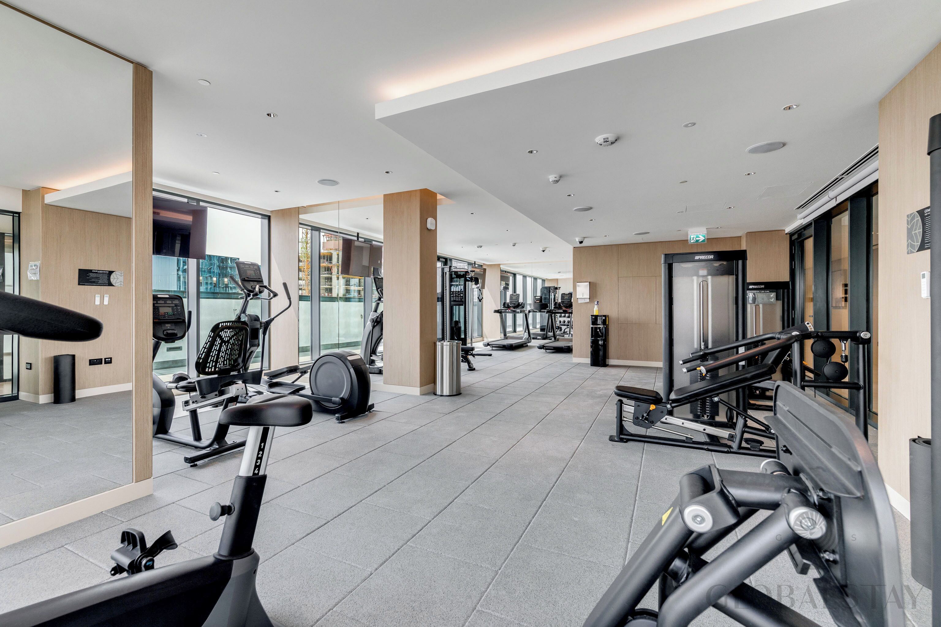 Une salle de sport moderne, dotée d’équipements d’exercice, de grandes fenêtres et d’un aménagement propre et spacieux.