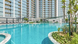A swimming pool with a clear blue water, surrounded by a modern building with balconies. - GLOBALSTAY. The Crest Tower C Apartments (Dubai)
