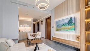 A modern living room with a sofa, a dining table, and chairs. There is a kitchen area in the background. - GLOBALSTAY. The Crest Tower C Apartments (Dubai)