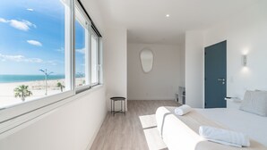Een moderne hotelkamer met een groot raam, een bed, een klein tafeltje en een deur.