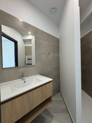 Une salle de bain moderne avec un grand lavabo, un miroir et un porte-serviettes.