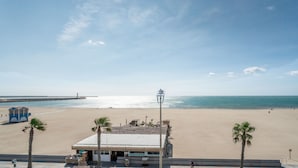 Uitzicht op een strand met een gebouw, palmbomen en een heldere lucht.
