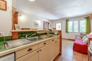 Une cuisine Ă©quipĂ©e dâun Ă©vier, dâun plan de travail et dâun coin repas avec une table et des chaises.