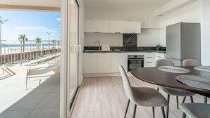 A modern kitchen with white cabinets, a dark countertop, and a dining area with a table and chairs.