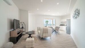 A modern living room with a TV, seating, and a view to the outside.