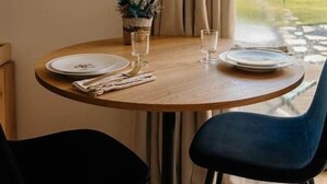A round wooden dining table with two black chairs, a small potted plant, and two glasses of water. - Lodge with a Pool (Pancé)