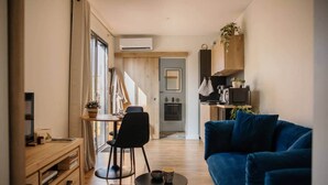 A modern living room with a blue sofa, a wooden coffee table, and a dining area with a table and chairs. - Lodge with a Pool (Pancé)
