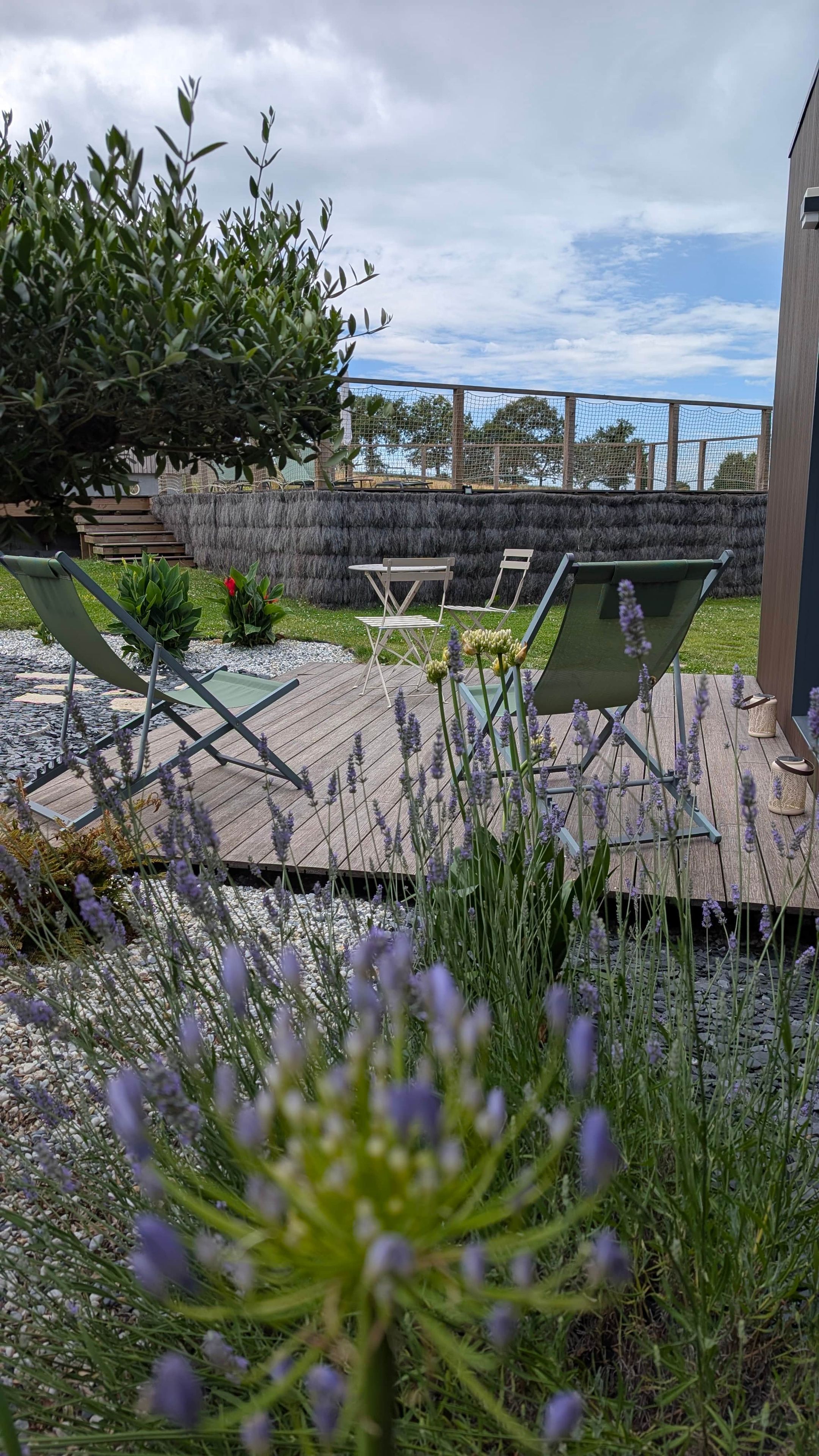 An outdoor seating area with a wooden deck, lounge chairs, and a view of the sea.