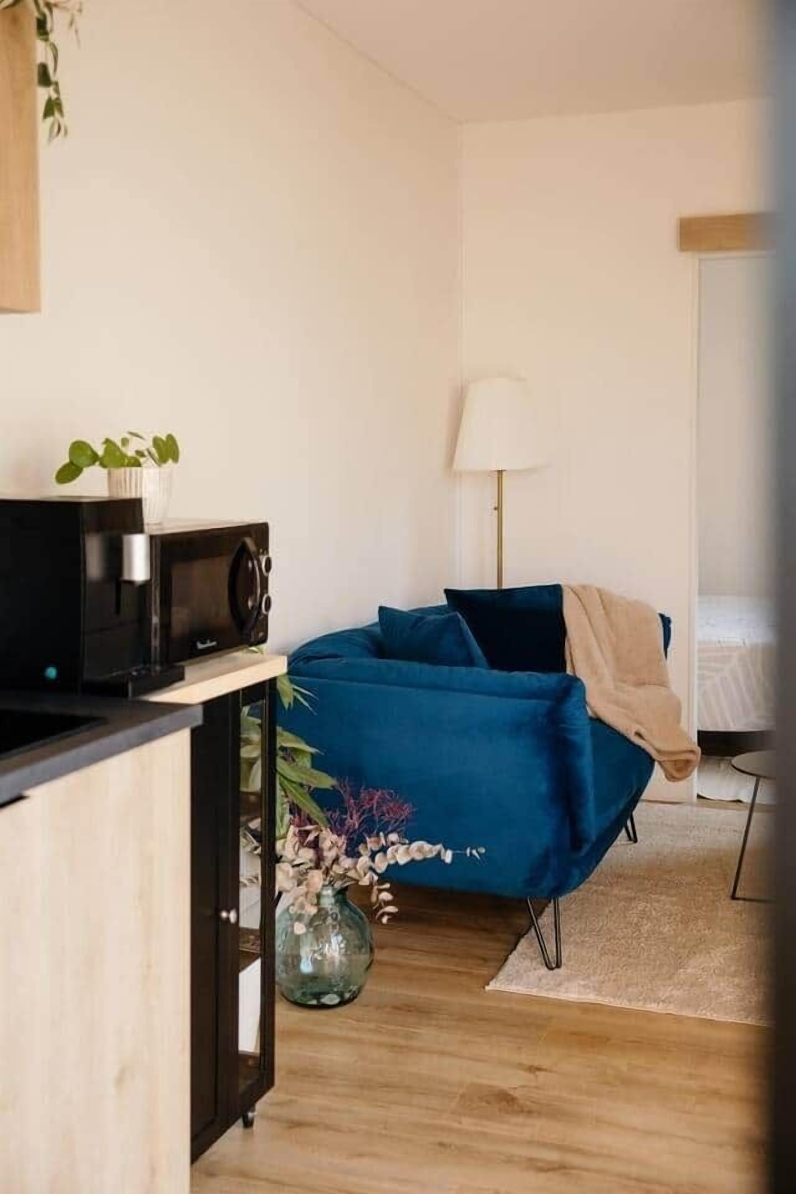 Une petite chambre comprenant un lit, une petite table de chevet, une lampe et un four à micro-ondes posé sur une étagère.