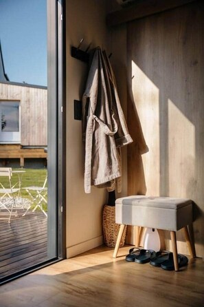 A modern bathroom with a wooden floor, a bench, and a towel rack with a robe. - Lodge with a Pool (Pancé)