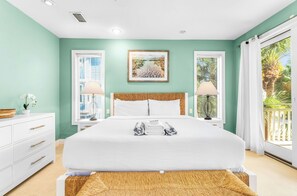 Quarto com uma cama, duas mesinhas de cabeceira, um criado-mudo, uma janela com cortinas e vista para o verde lá fora.