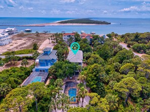 A coastal property with a swimming pool, multiple buildings, and a beach.