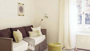 Ein gemütliches Schlafzimmer mit einem Bett, einem kleinen Nachttisch, einer Lampe, einem Wanddekor und einem Fenster mit Vorhängen.