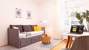 Ein modernes Wohnzimmer mit einem grauen Sofa, einem kleinen runden Tisch und einem Laptop auf einem wei ßen Schreibtisch.