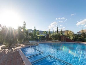 A swimming pool with a clear blue water surface, surrounded by a brick deck and metal pool ladders.