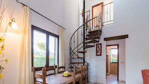 A dining area with a wooden table and chairs, a spiral staircase, and a view of greenery outside. - Holiday Home Ibipozo With Pool (Pozo Alcon)