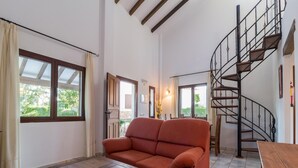 A living room with a sofa, a wooden coffee table, a spiral staircase, and large windows. - Holiday Home Ibipozo With Pool (Pozo Alcon)