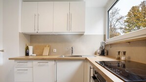 Una cocina moderna con armarios blancos, encimera de madera, estufa integrada y ventana.