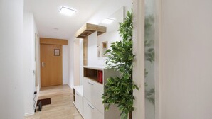 Un pasillo con una puerta de madera, un armario blanco y una planta verde.